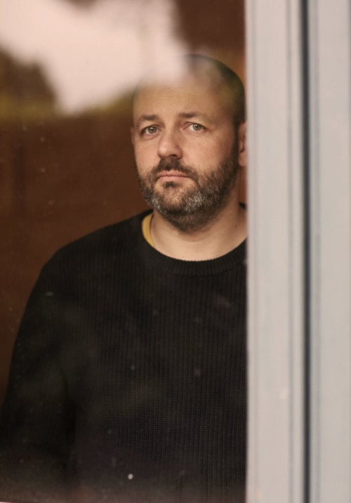 Color photograph of poet Sebastien Smirou looking out of a window