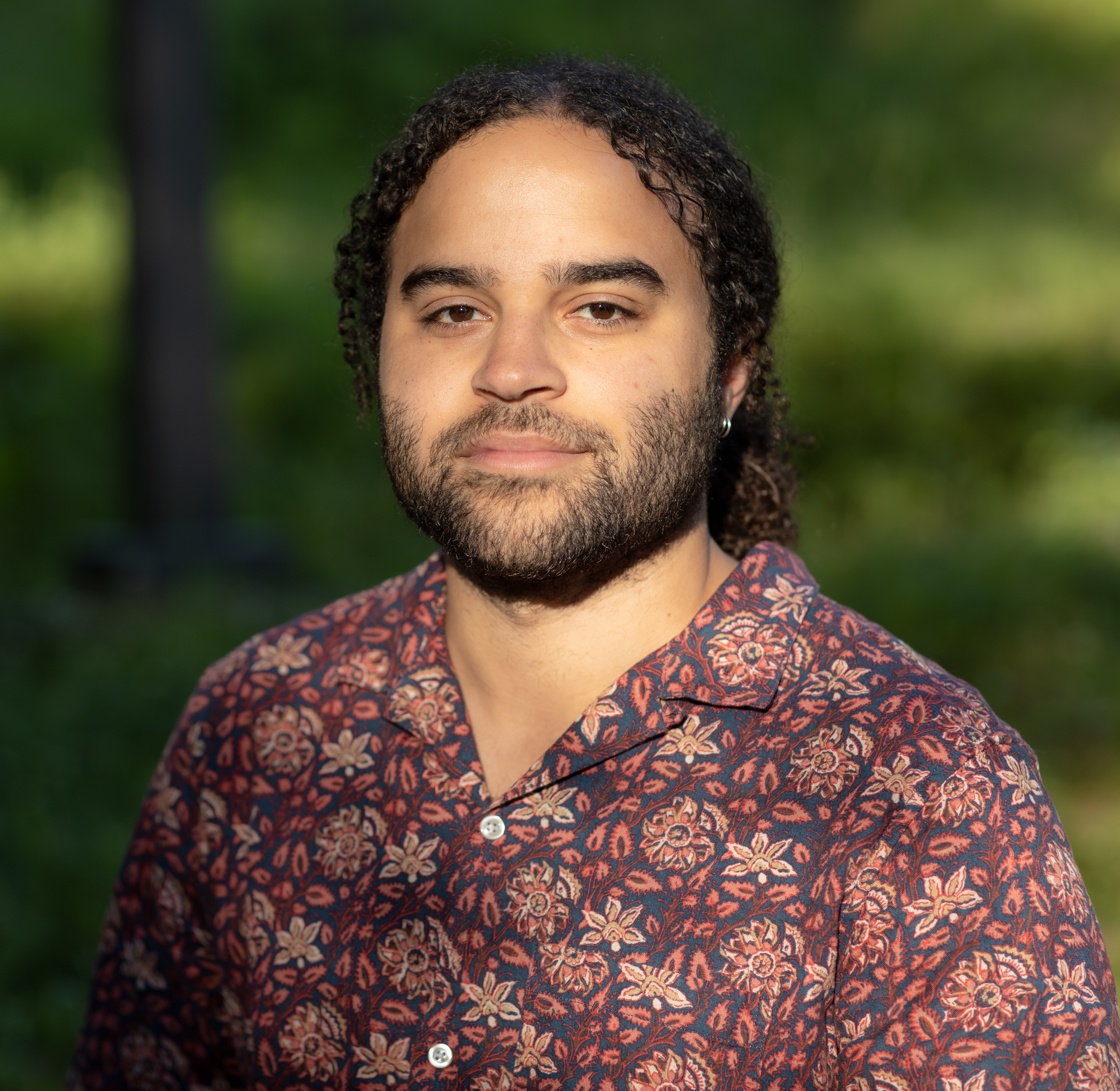 An image of the poet, Steffan Triplett. A young man with long hair and medium dark skin.